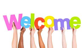 Colorful "Welcome" sign being held up by multiple hands.